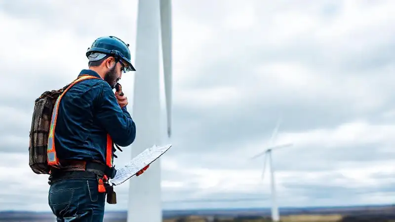 Técnico revisa torre eólica con seguridad
